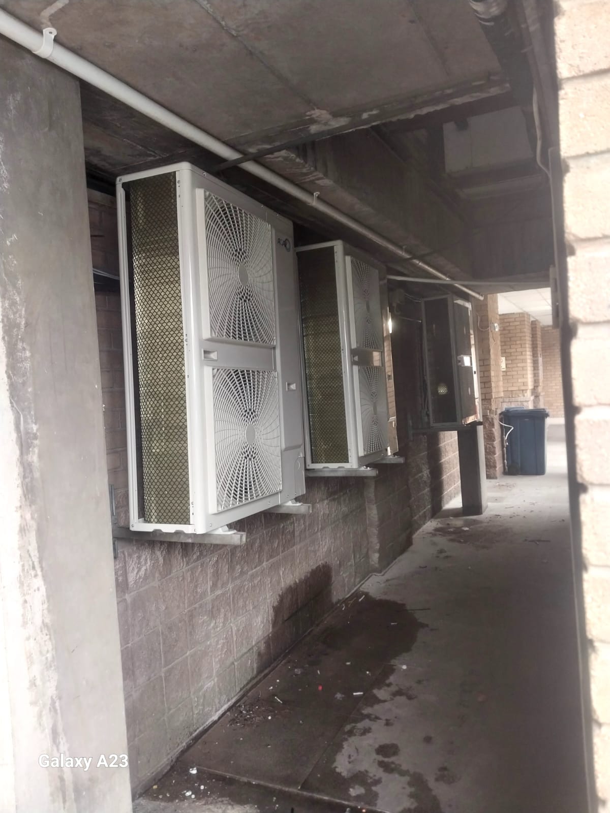 Multiple outdoor condensers installed along a building corridor